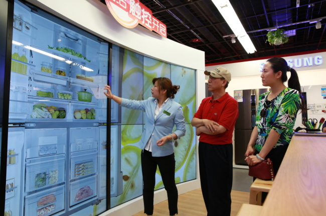 A Samsung Electronics employee introduces customers to home electronics products displayed at the Samsung Open House, an experience store that opened in Beijing last month. The tech giant will open the shop in global markets including the U.S. and some European nations this year.   Samsung Electronics
