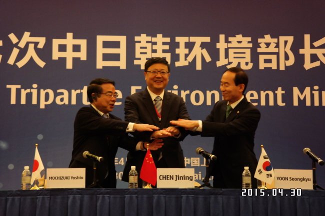 From right: The environment ministers of South Korea, China and Japan, Yoon Seong-kyu, Chen Jining and Mochizuki Yoshio, join hands after signing the Tripartite Joint Action Plan at the 17th Tripartite Environment Ministers Meeting in Shanghai on Thursday. Environment Ministry
