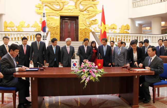 Korean Trade Minister Yoon Sang-jick (left) and his Vietnamese counterpart Vu Huy Hoang sign a bilateral free trade agreement in Hanoi, Vitenam, Tuesday. The trade pact is expected to take effect this year.   Yonhap