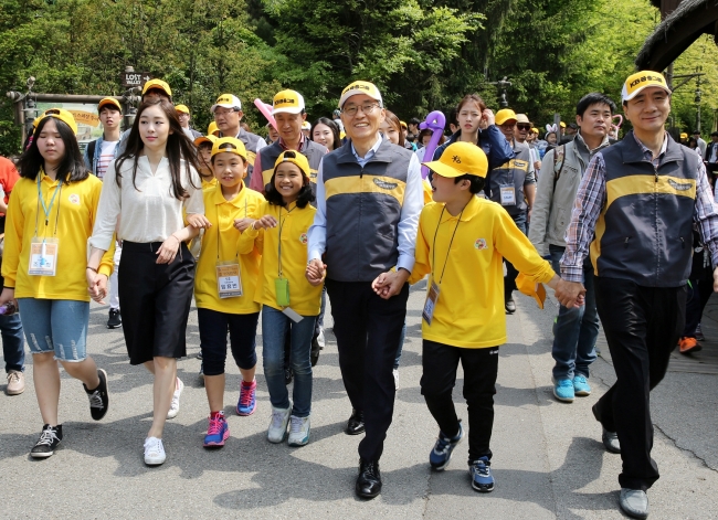 KB Financial Group chairman Yoon Jong-kyoo (fifth from left) and former figure skater Kim Yu-na (second from left) walk with children in Everland, Gyeonggi Province. Celebrating family month and Children’s Day, the banking group held a cultural camp program on Friday to Saturday for children from multicultural families.   KB Financial