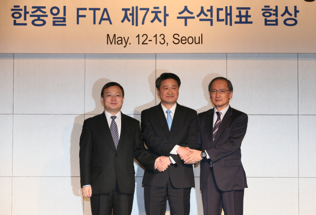 Korea’s chief negotiator Kim Hak-do (center) poses with his Chinese counterpart Wang Shouwen (left) and Japanese counterpart Yasumasa Nagamine ahead of the opening of talks on a trilateral free trade pact in Seoul on Tuesday.   Yonhap
