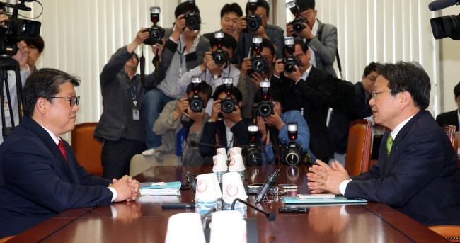 Reps. Cho Won-jin (left) of the ruling Saenuri Party and Kang Gi-jung of the main opposition New Politics Alliance for Democracy discuss civil service pension reforms at the National Assembly on Wednesday.   Yonhap
