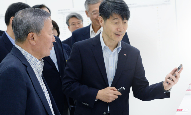 LG Group chairman Koo Bon-moo (left) listens to LG Electronics mobile chief Cho Ju-no about the company’s new flagship smartphone, the G4, at an R&D campus in Seoul on Wednesday. Koo inspected LG’s some 70 new products and discussed ways to elevate their competitiveness.   LG Group