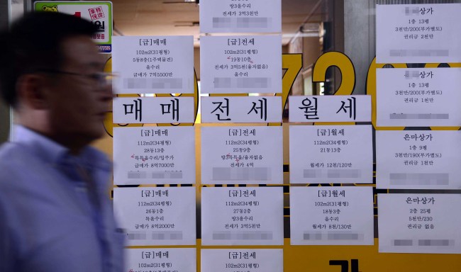 주택시장이 활기를 띠고 있지만 주의해야할 점도 많다. 한 행인이 중개업소 앞을 지나가고 있다.