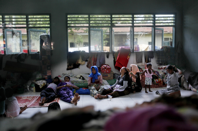 Rohingya migrants sit inside their temporary shelter in Bayeun, Aceh province, Indonesia, Sunday, May 24, 2015. Thousands of migrants - about half of them Bangladeshi and the others minority Rohingya Muslims from Myanmar - have landed ashore in Indonesia, Malaysia and Thailand since May 10. Thousands more are believed to be trapped at sea, and the United Nations has warned that time is running out. (AP-Yonhap)