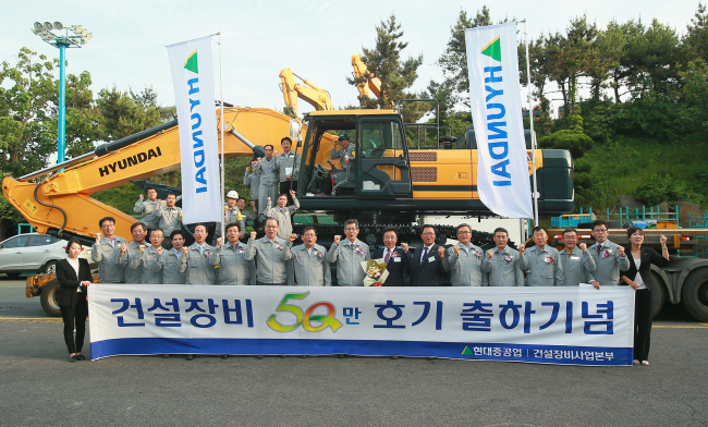 Executives and workers at Hyundai Heavy Industries celebrate the export of its 500,000th piece of construction equipment at its headquarters in Ulsan on Tuesday.   HHI