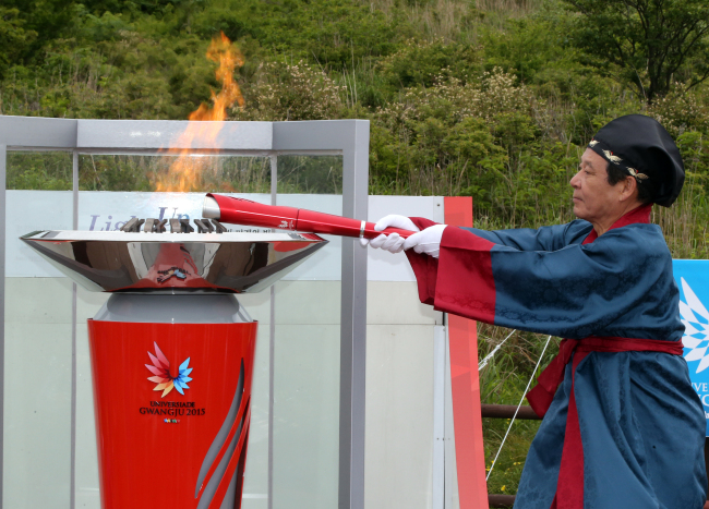 <YONHAP PHOTO-1407> 무등산에서 채화된 U대회 성화 (광주=연합뉴스) 박철홍 기자 = 2015광주하계유니버시아드를 밝힐 성화가 2일 오전 광주 무등산 장불재에서 채화돼 보존성화로에 옮겨지고 있다. 2015.6.2 pch80@yna.co.kr/2015-06-02 12:45:00/ <저작권자 ⓒ 1980-2015 ㈜연합뉴스. 무단 전재 재배포 금지.>
Gwangju Mayor Yoon Jang-hyun lights the flame with the “Wings of Light” torch for the World University Games, which will kick off on July 3 in Gwangju.   Yonhap