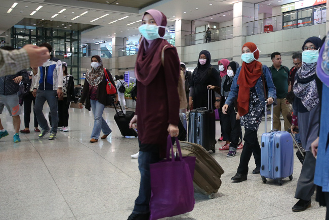 Indonesian visitors donning masks enter Korea via Incheon International Airport on Sunday, amid escalating fears over MERS.   Yonhap