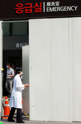 Staff members of Samsung Medical Center in southern Seoul enter the hospital’s emergency room through the quarantine fence on Monday. (Yonhap)