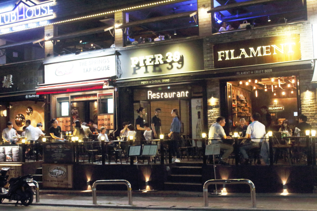 People sit outside at pubs and restaurants on Gyeongnidan-gil, Yongsan.