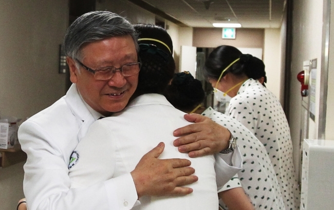 Park Chang-il, director of Konyang University Hospital in Daejeon, hugs the medical staff after the hospital reopened Friday. (Yonhap)