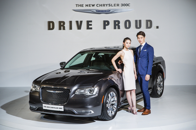Models pose next to the new Chrysler 300C, Chrysler’s next generation full-size luxury sedan presented by Fiat Chrysler Automobiles Korea in Seoul on Tuesday.     FCA Korea