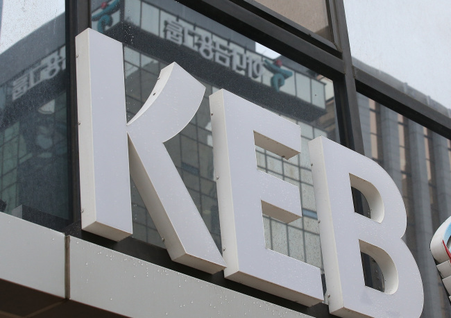 The Hana Financial Group building is reflected in the window of a KEB office in Seoul. (Yonhap)