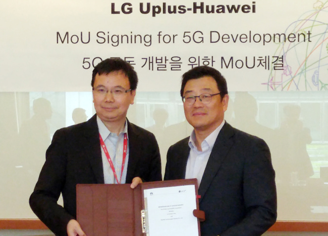 Kim Sun-tae (right), executive vice president of LG Uplus’ service development division, and Yang Chao Bin, chief marketing officer of Huawei, pose at a signing ceremony of a memorandum of understanding in Shanghai on Tuesday.   LG Uplus