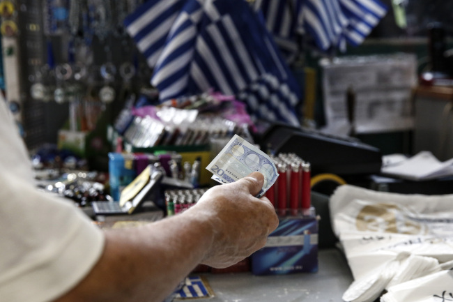 A customer offers a 20 euro note in payment for goods purchased inside a one euro store in Athens, Greece, on Friday, July 17, 2015. Germany's Parliament is set to ratify bridge financing and the start of talks for a three-year rescue plan. (Bloomberg)