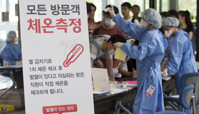 　Visitors are checked for their body temperature by health care workers at Samsung Medical Center, one of the MERS-affected hospitals that resumed normal services on Monday. Yonhap
