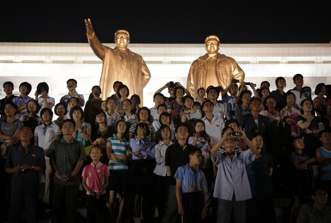 The bronze statues of the late North Korean leaders Kim Il Sung and Kim Jong Il tower over people as they watch fireworks explode, Monday, July 27, 2015, in Pyongyang, North Korea as part of celebrations for the 62nd anniversary of the armistice that ended the Korean War. (AP-Yonhap)