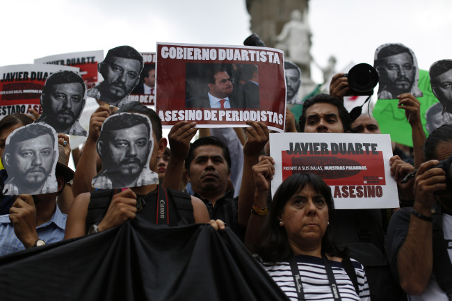 <YONHAP PHOTO-0453> Journalists and activists hold up cut-out images of slain photojournalist Ruben Espinosa during a protest at MexicoCity's Angel of the Independence monument, Sunday, Aug. 2, 2015. Mexico City officials said Sunday they are pursuing all lines of investigation into the killing Espinosa and four other women whose bodies were found in the capital, where he had fled from the state of Veracruz because of harassment. According to the Committee to Protect Journalists, 11 journalists have been killed there since 2010, all during the administration of Gov. Javier Duarte. The signs held by the protesters read in Spanish "Duarte Government, Murderer of Journalists" and "Javier Duarte, Assassin State." (AP Photo/Dario Lopez-Mills)/2015-08-03 07:54:40/ <저작권자 ⓒ 1980-2015 ㈜연합뉴스. 무단 전재 재배포 금지.>