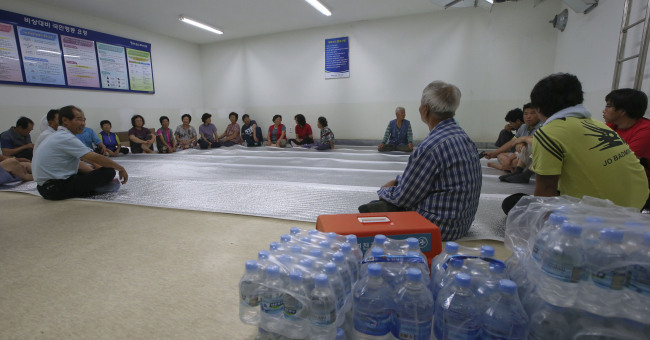 <YONHAP PHOTO-1729> 민통선 안 대피소 (연천=연합뉴스) 임병식 기자 = 북한이 전선일대에 '준전시상태'를 선포한 가운데 21일 경기도 연천군 민통선 내 횡산리 대피소에서 마을 주민들이 모여 앉아 있다. 2015.8.21 andphotodo@yna.co.kr/2015-08-21 13:03:30/ <저작권자 ⓒ 1980-2015 ㈜연합뉴스. 무단 전재 재배포 금지.>
South Korean residents remain seated at an underground bunker in Yeoncheon, Gyeonggi Province, Friday, as they were urged to evacuate by authorities concerned about North Korea’s additional provocations.   Yonhap