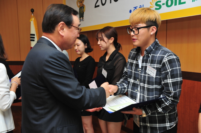S-OIL HONORS FIREFIGHTERS' SACRIFICE -- S-Oil deputy CEO Kim Dong-cheol (left) delivers 210 million won ($177,000) in scholarships to the children of firefighters who died while on duty in a ceremony held at the Yeongdeungpo Fire Station in Seoul on Wednesday. Since 2006, S-Oil has delivered 2.8 billion won in scholarships to 978 students as part of its efforts to support the families of deceased firefighters in South Korea. (S-Oil)
