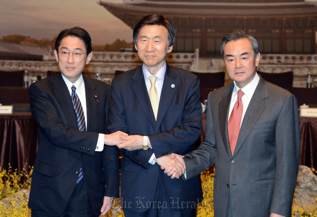 Seoul’s Foreign Minister Yun Byung-se (center) and his Chinese and Japanese counterparts, Wang Yi (right) and Fumio Kishida, respectively, pose after their meeting on March 22 in Seoul. (Yonhap)