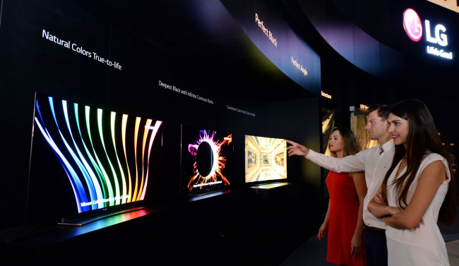 Models look at the media wall made of 64 OLED TVs at LG Electronics’ exhibition booth at the venue of the IFA Electronics trade show, set to kick off Friday in Germany. (LGE)
