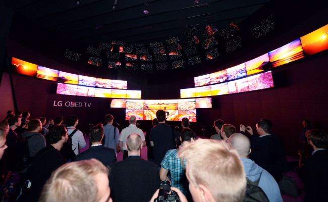 Visitors look at the video presentation played on 64 OLED TVs at the company’s IFA exhibition hall. 	LG Electronics