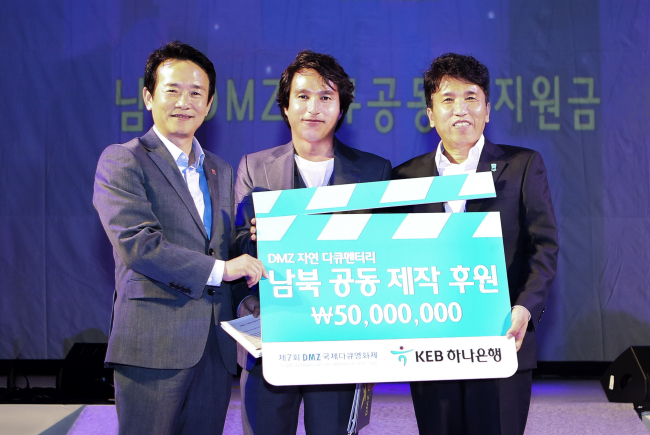 17일 저녁 민통선 내 캠프 그리브스에서 열린 'DMZ 국제다큐멘터리 영화제' 개막식에서 함영주 KEB하나은행장(사진 오른쪽)이 남경필 경기도지사(조직위원장, 사진 왼쪽), 배우 조재현(집행위원장, 사진 가운데)에게 영화제 후원에 더해 별도로 '남북 공동 DMZ 자연 다큐멘터리' 제작 비용 후원금 5000만원을 전달하고 있는 모습.
사진=KEB하나은행 제공