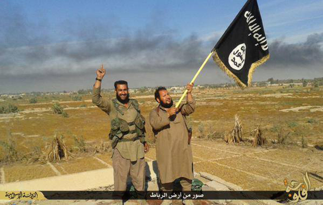 In this photo released on Sunday by a website of Islamic State militants, an Islamic State militant waves his group’s flag as he and another celebrate in Fallujah, Iraq, west of Baghdad. (Yonhap-AP)
