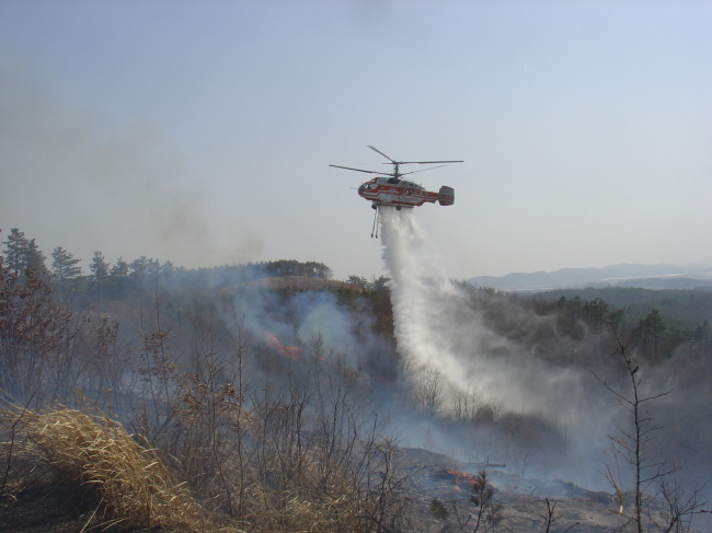 A helicopter fights a fire in a mountainous region. (KFS)