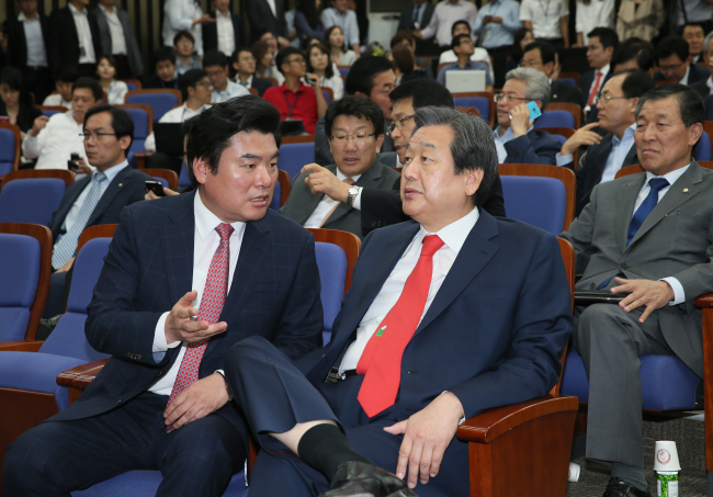 Saenuri leader Kim Moo-sung (right) speaks with Rep. Won Yoo-chul during the ruling party's general assembly held at the National Assembly on Wednesday. (Yonhap)