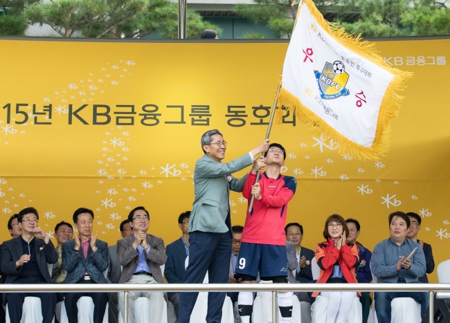 <YONHAP PHOTO-0867> 2015년 KB금융그룹 동호회 올림픽 (서울=연합뉴스) 윤종규 KB금융그룹 회장이 지난 3일 천안연수원에서 열린 '2015년 KB금융그룹 동호회 올림픽' 개회에 앞서 지난 대회 축구 우승팀 대표에게 우승기를 받아 함께 흔들고 있다. 2015.10.4 << KB금융그룹>> photo@yna.co.kr/2015-10-04 09:18:04/ <저작권자 ⓒ 1980-2015 ㈜연합뉴스. 무단 전재 재배포 금지.>