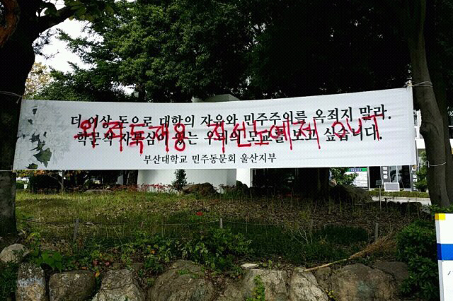 Graffiti that says, “Abolish the direct election system (of university president)” is scribbled on a placard supporting the direct voting system at the Pusan National University campus Thursday.   Yonhap