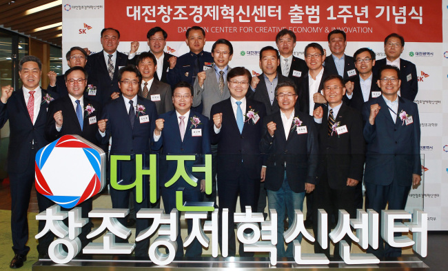 FIRST ANNIVERSARY OF SK DAEJEON INNOVATION CENTER -- Science, ICT and Future Planning Minister Choi Yang-hee (fourth from right, front row), Daejeon Mayor Kwon Seon-taek (fourth from left, front row), SK Telecom CEO Jang Dong-hyun (second from left, front row) and other officials celebrate the one-year anniversary of the Daejeon Creative Economy Innovation Center established by the government and SK Group at the center in Daejeon on Tuesday. (Yonhap)