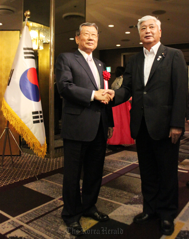 Japanese Defense Minister Gen Nakatani (right) shakes hands with Korean Ambassador to Japan Yoo Heung-soo during an Armed Forces Day celebration at the embassy in Tokyo on Oct. 2. (Yonhap)