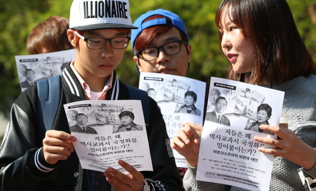 <YONHAP PHOTO-2453> 한국사 교과서 국정화 반대 전단지 보는 대학생들 (서울=연합뉴스) 홍해인 기자 = 14일 오후 서울 성북구 안암로 고려대학교 인문사회캠퍼스 내 민주광장에서 이 대학 총학생회 주최로 열린 한국사 교과서 국정화 결정 반대 기자회견에서 이를 지켜보는 학생들이 총학생회 측이 나눠준 전단지를 살펴보며 대화하고 있다. 2015.10.14 hihong@yna.co.kr/2015-10-14 15:12:15/ <저작권자 ⓒ 1980-2015 ㈜연합뉴스. 무단 전재 재배포 금지.>
College students look at a leaflet handed out Wednesday by the student body opposing the government’s decision to reinstate state-authored history textbooks for secondary schools at Korea University in Anam-dong, Seoul.   Yonhap