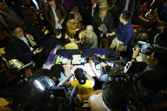 <YONHAP PHOTO-2287> 배우자 만나러 온 이순규 할머니 (속초=연합뉴스) 김도훈 기자 = 제20차 이산가족 상봉을 하루 앞둔 19일 오후 강원도 속초시 한화리조트에서 이순규(85) 할머니가 이산가족 접수를 하고 있다. 이 할머니는 이번 상봉행사에서 북측에 있는 남편 오인세(83) 할아버지를 만난다. 남북 이산가족 상봉행사에 참가하는 남측 가족들은 이날 속초한화리조트에 집결해 방북과 이산가족 상봉행사 절차 등에 대한 교육을 받고 다음날 오전 동해선 육로를 통해 금강산으로 이동해 꿈에 그리던 가족들을 만난다. 2015.10.19 superdoo82@yna.co.kr/2015-10-19 14:42:22/ <저작권자 ⓒ 1980-2015 ㈜연합뉴스. 무단 전재 재배포 금지.>
Lee Soon-gyu (center, sitting), 85, is surrounded by officials and the press as she registers with the Korean Red Cross on Monday at Hanwha Resorts in Sokcho, Gangwon Province, where the participants gathered for the separated family reunions to be held at Mount Geumgangsan in North Korea from Tuesday. Lee is set to be reunited with her husband Oh In-se, 83.   Yonhap