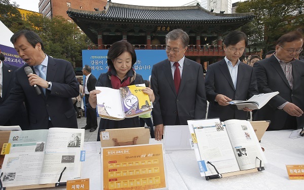 Opposition lawmakers including New Politics Alliance for Democracy chairman Rep. Moon Jae-in (center) browse through Korean history textbooks displayed at an exhibition opened at Bosingak park in downtown Seoul as part of the rallies to oppose state-authored textbook on Sunday.  Yonhap