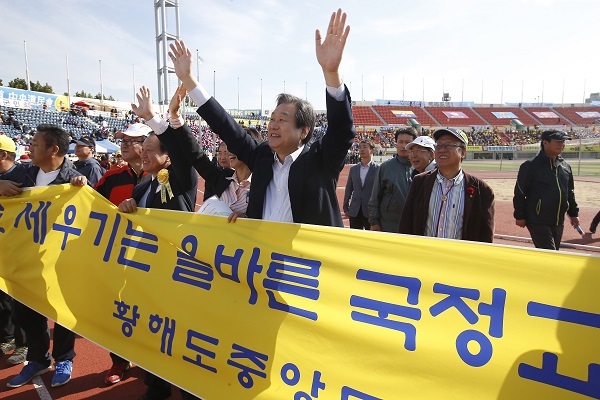 Ruling Saenuri Party chairman Rep. Kim Moo-sung (center) walk along with other participants with a banner promoting state-authored textbook at a presidential sports event gathering those originating from North Korean provinces and North Korean defectors at Mokdong Stadium in western Seoul, Sunday.  Yonhap