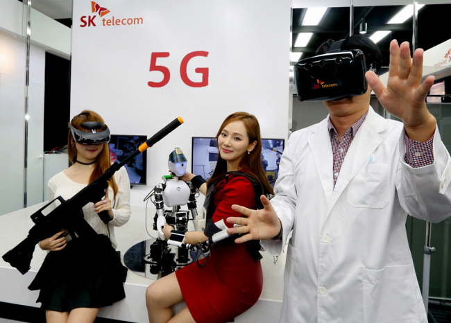 Models pose with virtual reality products at SK Telecom's 5G Playground, an R&D cetner, in Bundang, Gyeonggi Province on Thursday. SKT