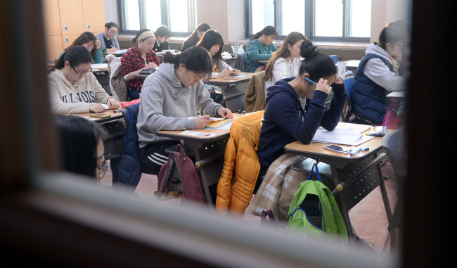 12일 오전 서울  용산구 용산고등학교 앞에서 후배들이 2016학년도 대학수학능력시험 응원전을 펼치고 있다.
Students get a last-minute read before the college entrance exam at a school in Seoul on Thursday.   Park Hyun-koo/The Korea Herald
