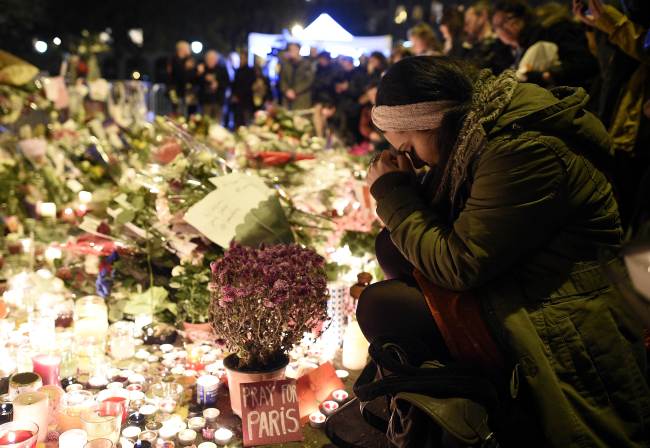 A woman prays at a makeshift memorial in front of the Bataclan theatre, one of the site of the attacks in Paris, on Nov. 15, in Paris. AFP-Yonhap News