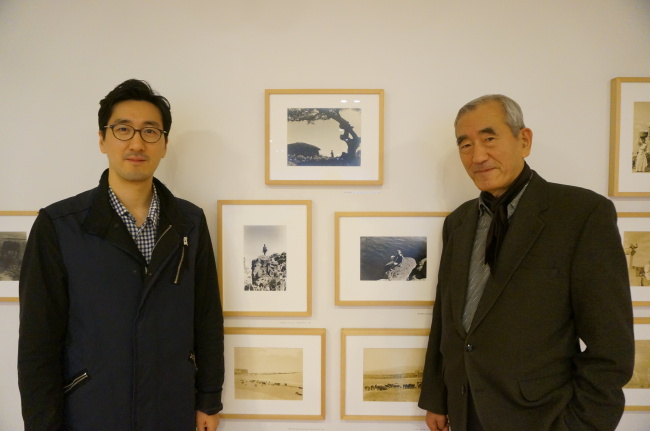 Father Lim Chung-eui (right) and son Lim June-young, third- and fourth-generation photographers, pose at Art Space J in Seongnam, Gyeonggi Province, which is exhibiting photos by four generations of Lim photographers.  (Lee Woo-young/The Korea Herald)