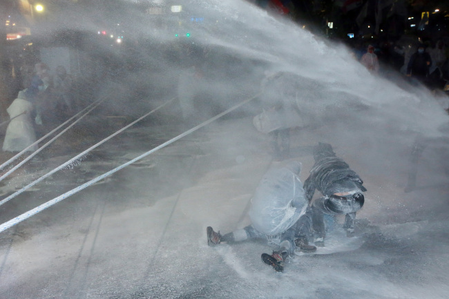 Two protestors look after a farmer who lies on the floor after being sprayed by a water cannon during the Nov. 14 antigovernment mass rally in Jongro-gu, Seoul in this file photo. (Yonhap)