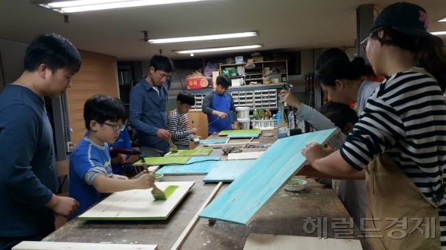 ▲목공 마을기업 아임우드에서 가족참가자들이 꿈씨어린이작은도서관 동아리실에 기증할 꼬마책상을 만들고 있다