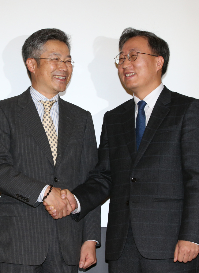 Yoon Ho-young (right), executive director of Kakao Corp., poses with Kim In-hoe, executive director of KT Corp., prior to a joint press conference in Seoul on Monday.   Yonhap