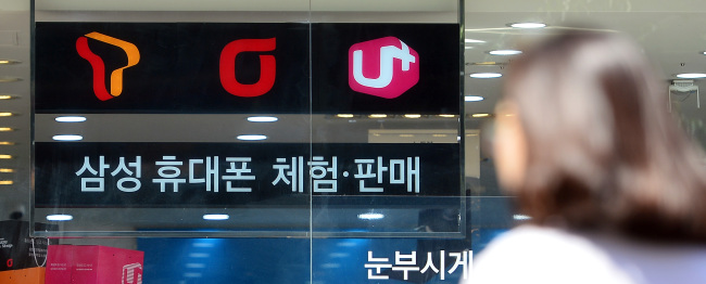 The logos of SK Telecom, KT and LG Uplus are seen at an electronics shop in Seoul.   Yonhap