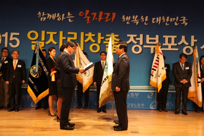 Starbucks Coffee Korea CEO Lee Seock-koo (right) receives a government order of merit from Employment and Labor Minister Lee Ki-kweon for the company’s contribution to job creation on Tuesday in Seoul. The coffee shop operator hires an average of 10 staff members for every new store, all with a regular work contract instead of part-time.   Starbucks Coffee Korea