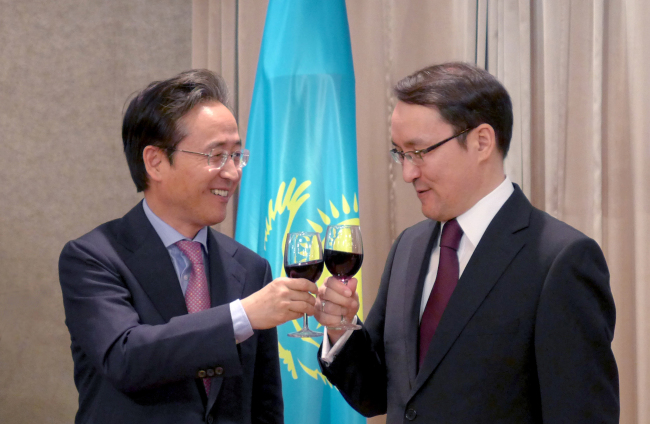 Shin Bong-kil (left), president of the Institute of Foreign Affairs and National Security, and Kazakh Ambassador Dulat Bakishev clink their glasses at a reception marking Kazakhstan’s National Day on Tuesday in Seoul.   Joel Lee/The Korea Herald