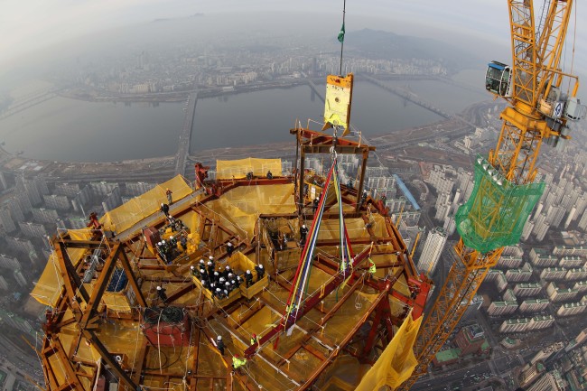 A ridge beam is placed on the roof of Lotte World Tower in a traditional ceremony to mark the completion of exterior work for the 123-story skyscraper Tuesday. (Yonhap)